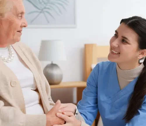 young-female-carer-wearing-blue-uniform-holding-female-patient-hand.
